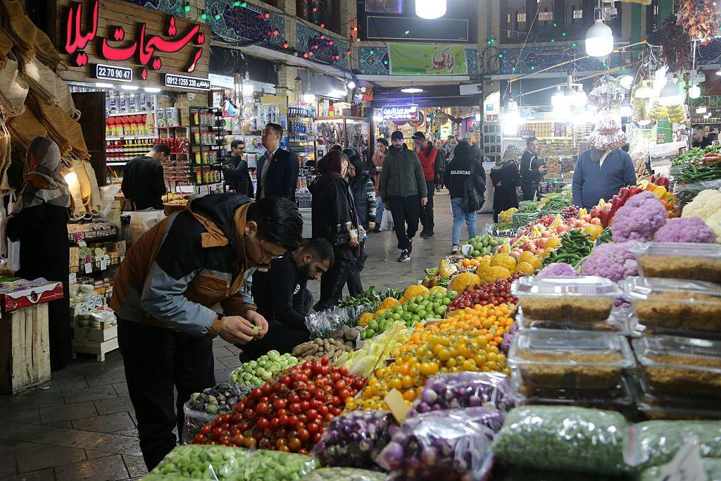سوق للخضراوات والمواد الغذائية في طهران ليلاً ويظهر فيه بعض المتسوقين من رجال ونساء