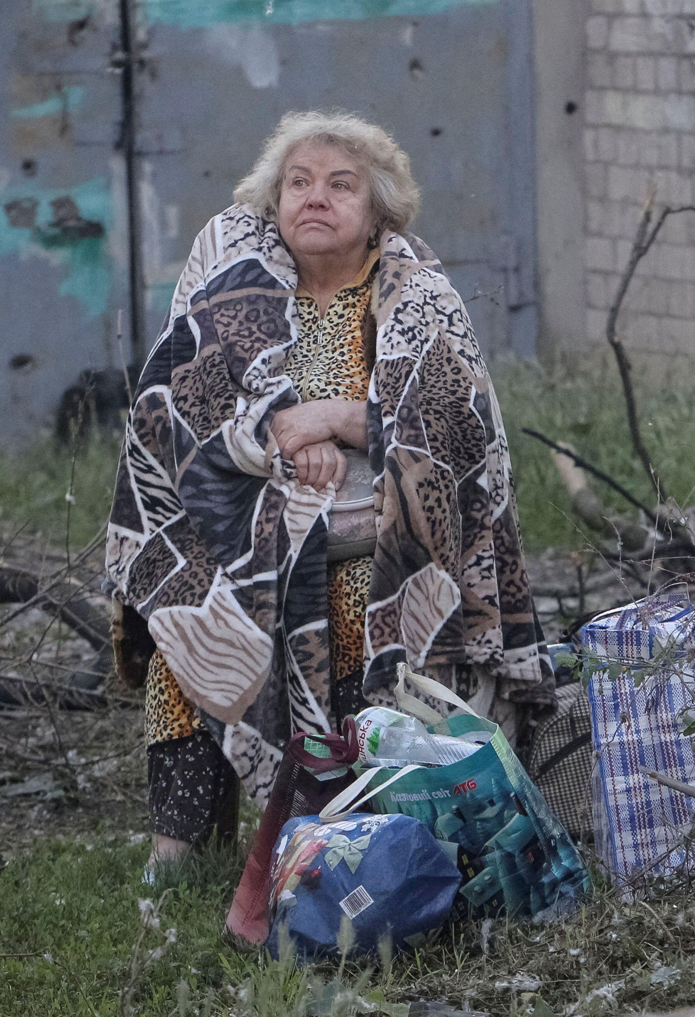 napad na ukrajinu, žena umotana u ćebe stoji na travi posle ruskog napada na dnjepar
