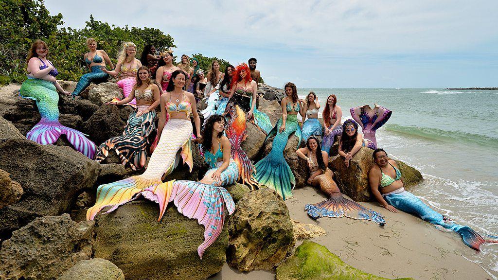 Grupo de mulheres vestidas com caudas de sereia posa para foto &agrave; beira d'&aacute;gua