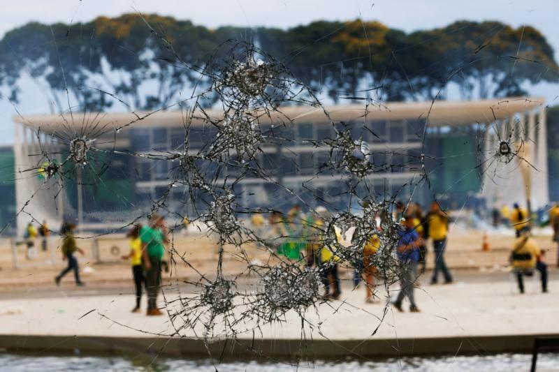 Janela quebrada com manifestantes ao fundo durante invasão do Palácio do Planalto em 8 de janeiro de 2023
