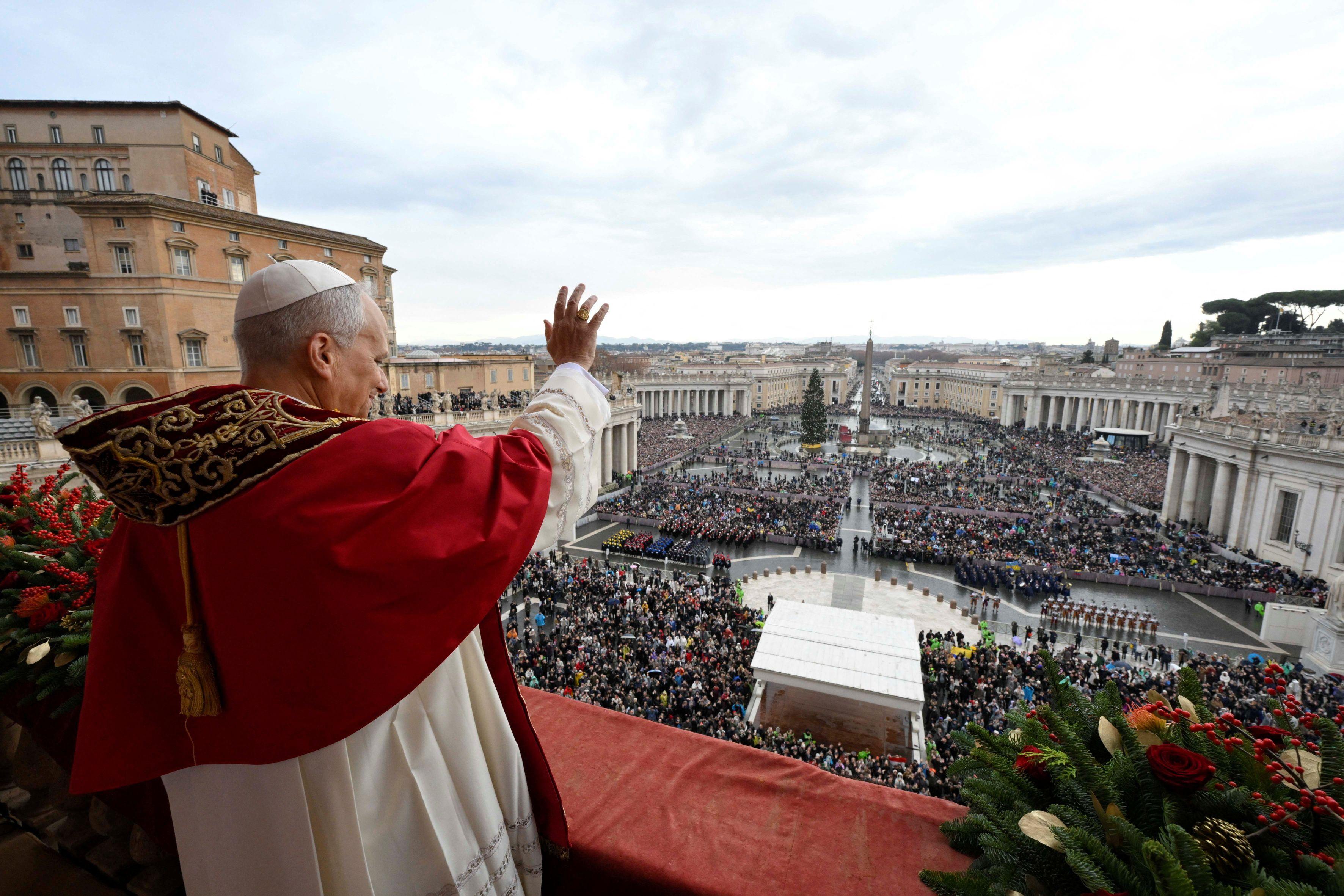 El papa León, con vestimentas papales blancas y rojas, saluda a las multitudes desde el balcón de la basílica de San Pedro el día de Navidad de 2025.