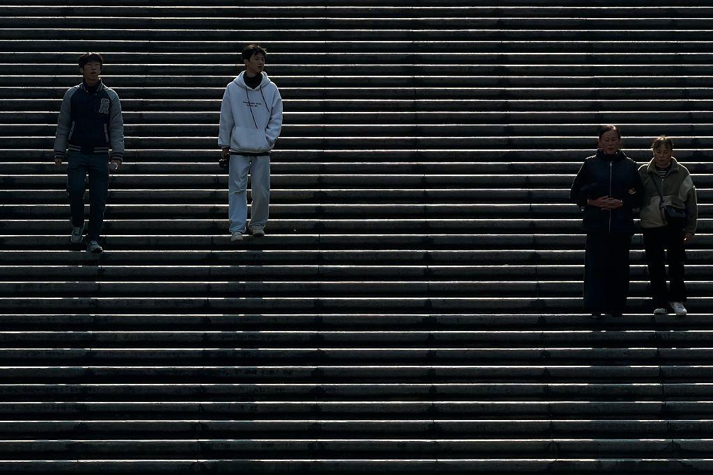 2025年11月26日，中國重慶，午後陽光灑在寬闊的戶外階梯上，人們沿著階梯往下走去。