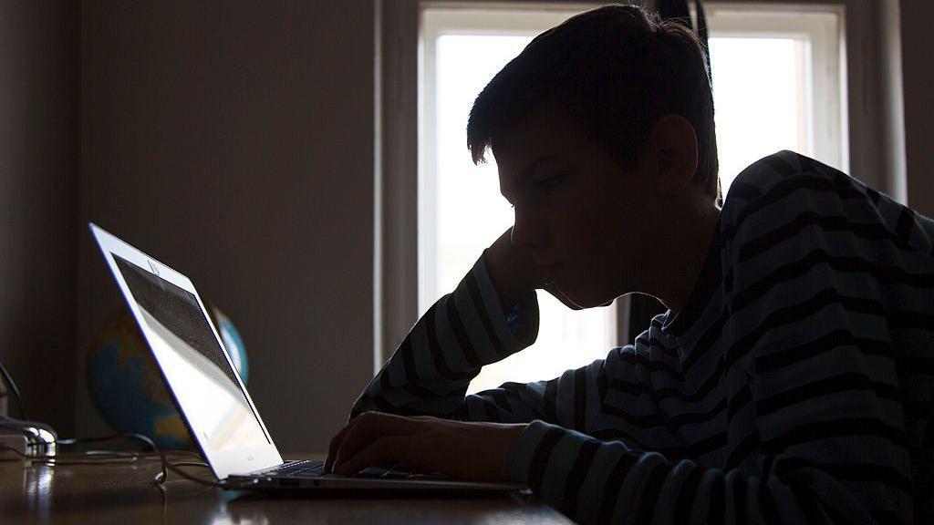 Adolescente olha para laptop em foto ilustrativa