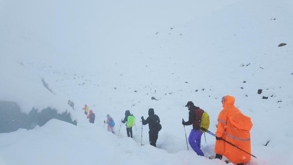 Pessoas em fila com roupas e equipamentos de neve e caminhando pela nevasca 