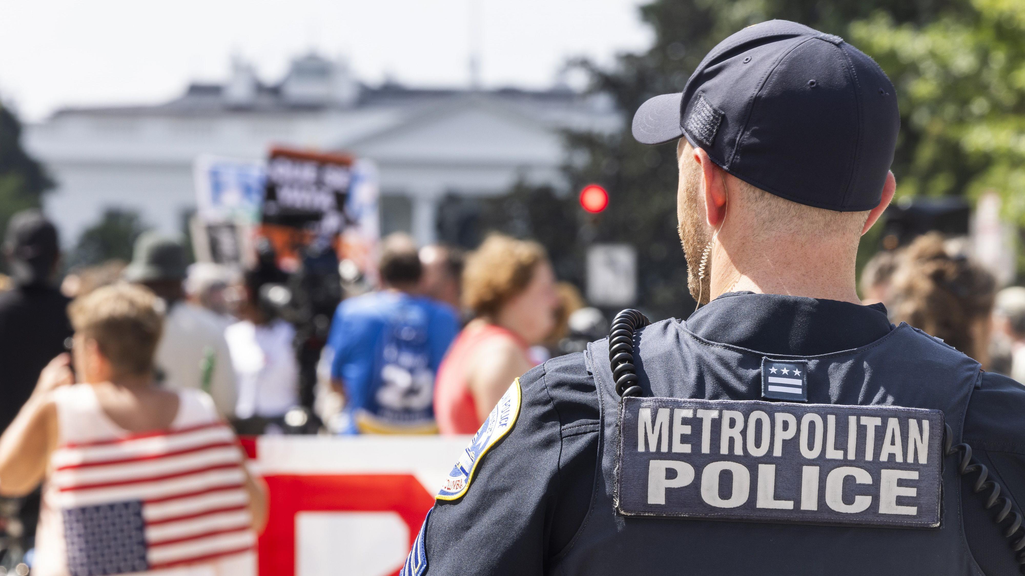 ضابط شرطة العاصمة واشنطن يراقب احتجاجات على قرار الرئيس الأمريكي دونالد ترامب بتحويل قوة شرطة العاصمة إلى قوة فيدرالية