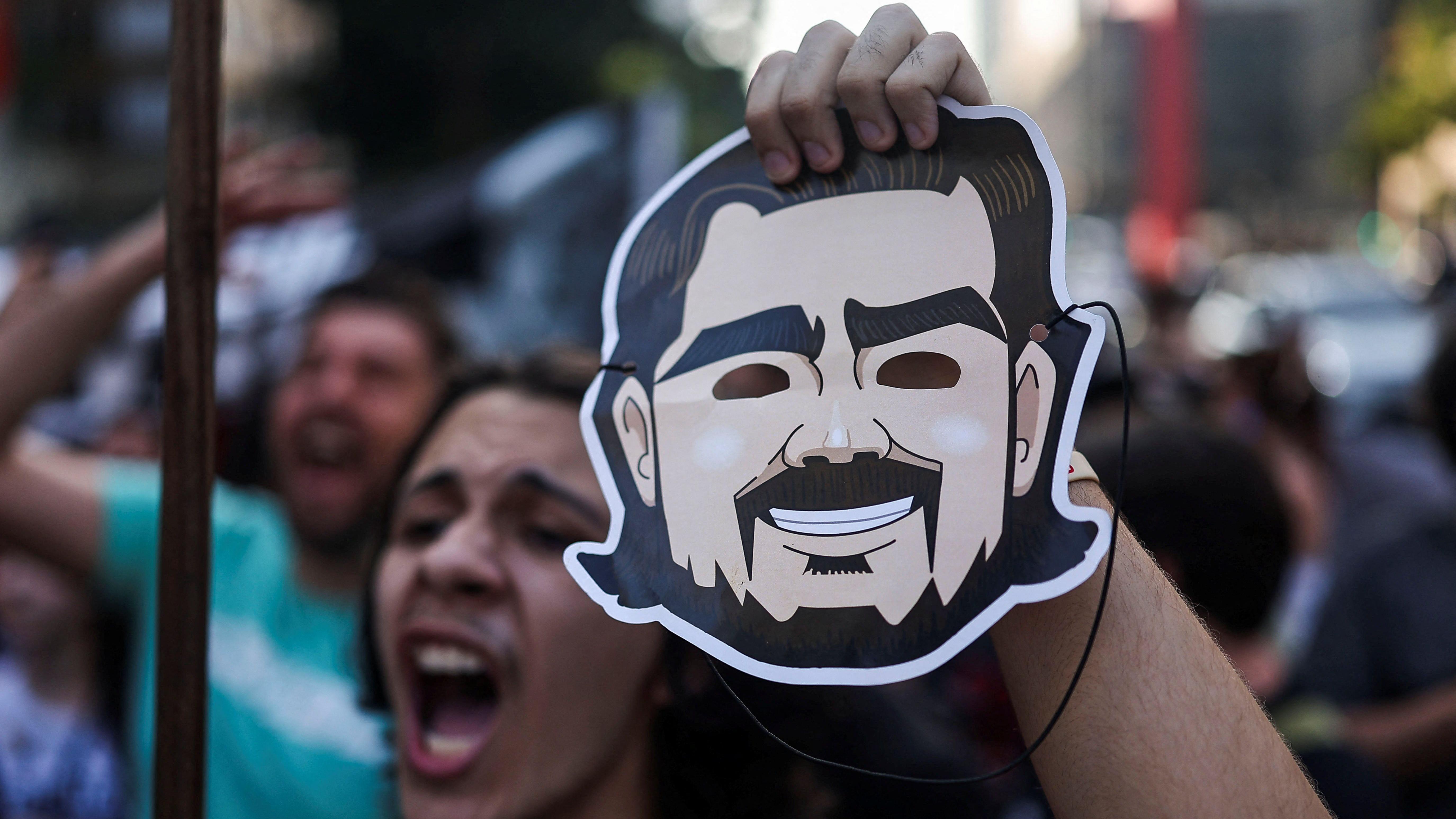 Um homem segura uma m&aacute;scara de Daniel Vorcaro em uma manifesta&ccedil;&atilde;o contra a corrup&ccedil;&atilde;o. 