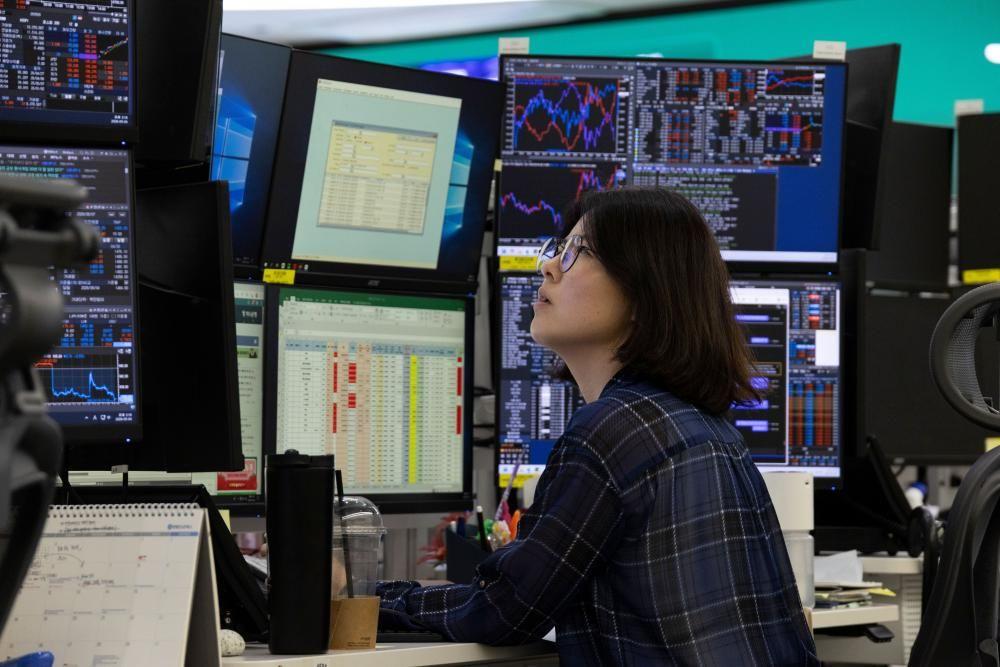 Una corredora de bolsa mira varios monitores con indicadores financieros