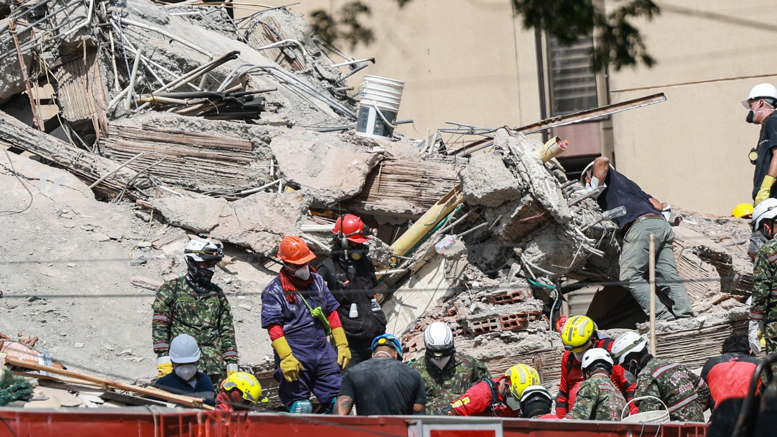 Socorristas com material de prote&ccedil;&atilde;o em um edif&iacute;cio desabado em Cali.