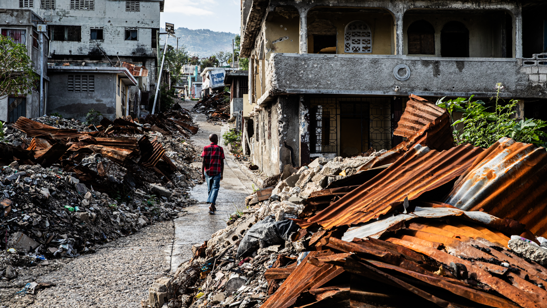 Homem caminha ao lado de casa em ru&iacute;nas e escombros no bairro de Solino, em Porto Pr&iacute;ncipe (Haiti), no dia 17 de fevereiro de 2026. Gangues atacaram a regi&atilde;o no final de 2024.
