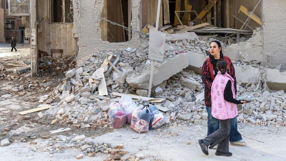 Mujer camina por los escombros de un edificio en Teherán