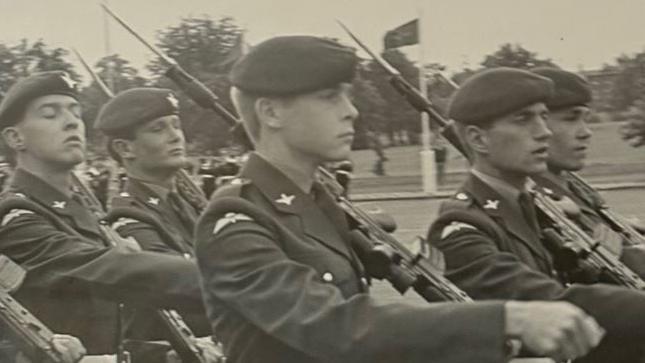 Imagem em preto e branco mostra jovens integrantes do Regimento de Paraquedistas marchando em um p&aacute;tio de formatura. Os soldados carregam fuzis SA80 com baionetas fixadas