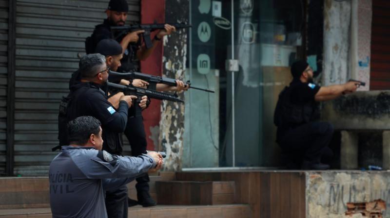 Cinco policiais fortemente armados posicionados perto de calçada e escadaria
