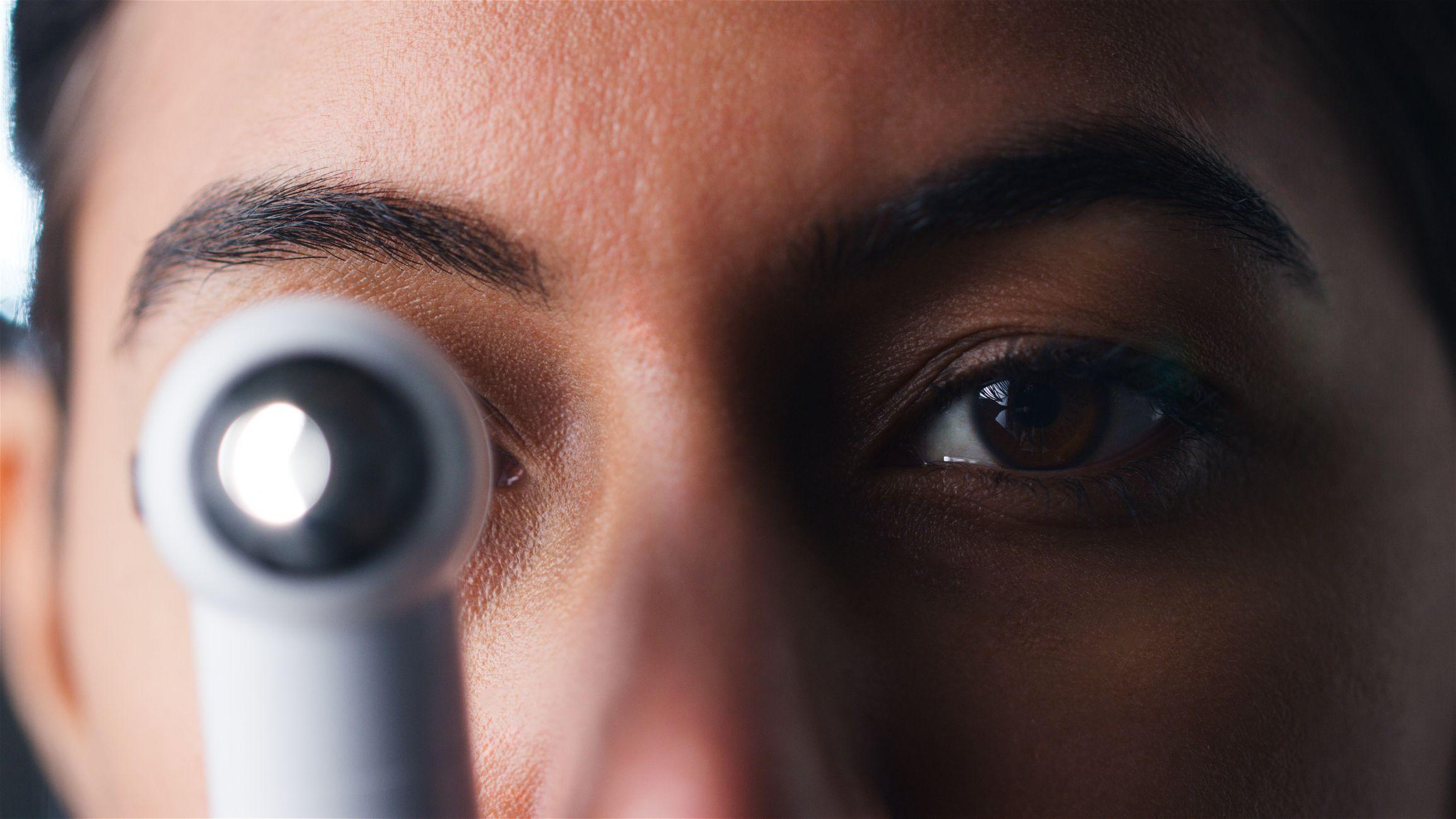 Equipamento de oftalmoscópio na frente de um dos olhos de uma mulher