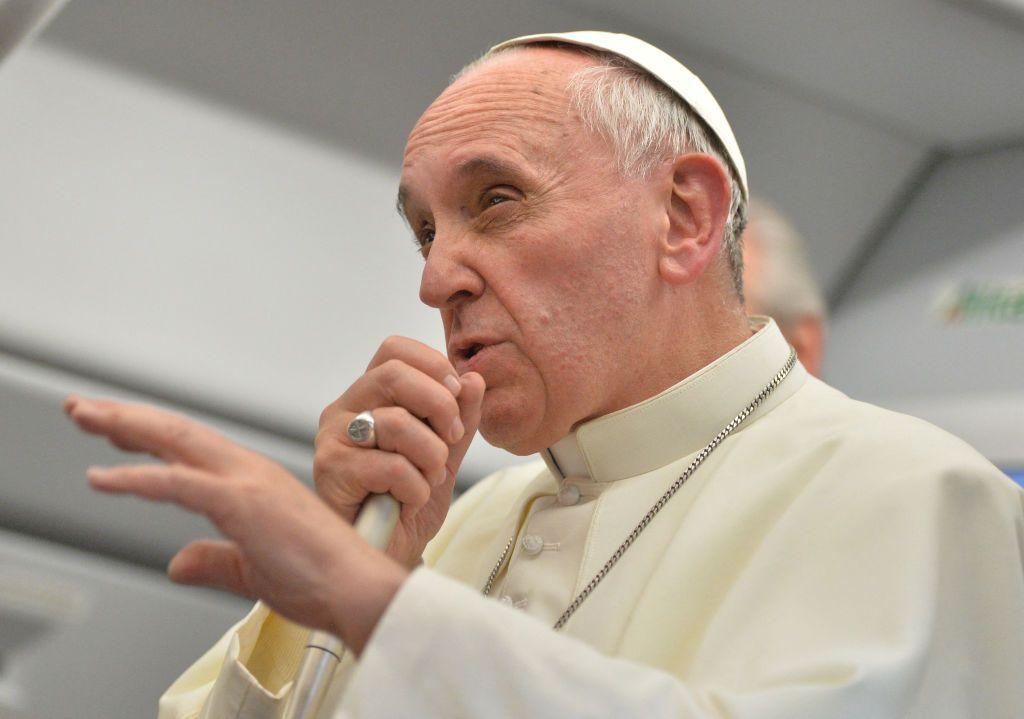 Papa discursa, com microfone na mão, dentro de avião