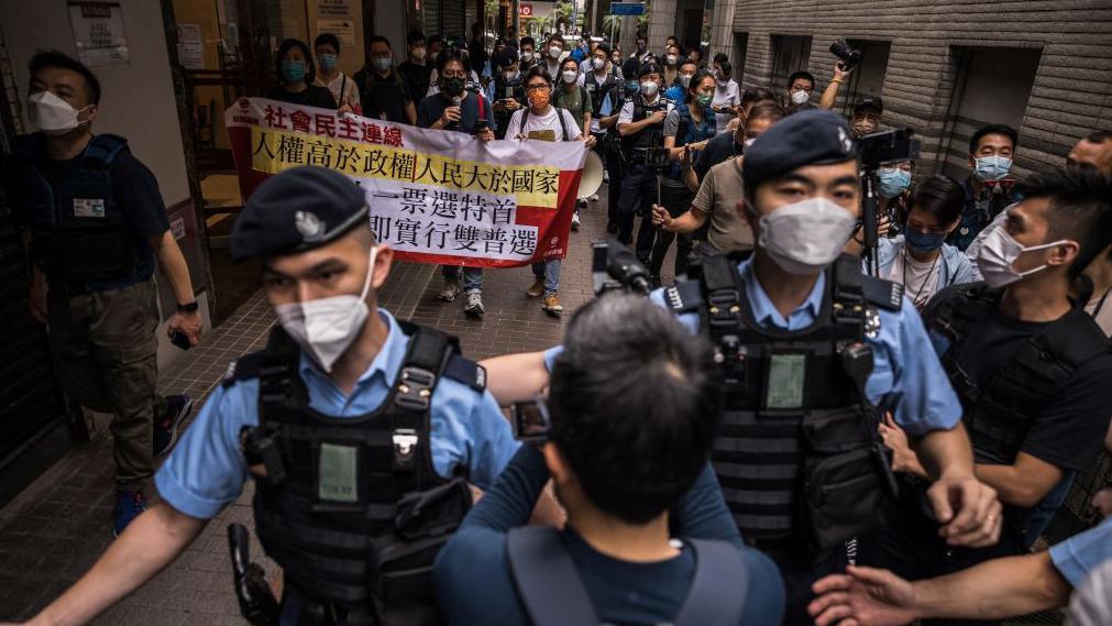 2022年5月8日，在香港行政長官選舉當日，社民連成員在街頭遊行，抗議其產生過程，警察在前方引領媒體。