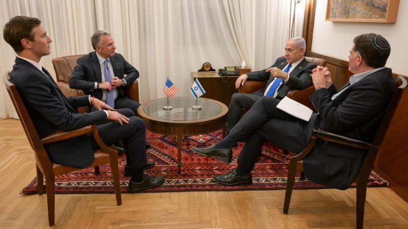 نتنياهو بجانبه يبدو أنه مسؤول إسرائيلي إذ يرتدي مع البدلة الرسمية " الكيباه" أو غطاء الرأس اليهودي، يظهر من الخلف. مقابل نتنياهو يجلس كل من ويتكوف وكوشنر. جميعهم يرتدون ملابس رسمية. على طاولة صغيرة في المنتصف العلم الإسرائيلي والعلم الأمريكي. الأرضية خشبية اللون وعليها سجادة لا تغطيها بالكامل لونها أحمر مزركش.