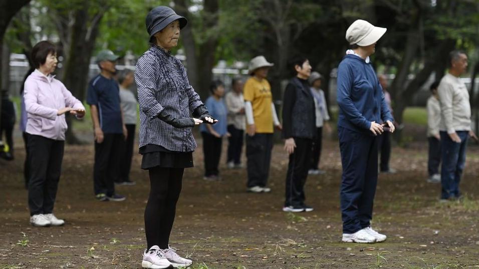Un grupo de personas mayores realizan ejercicio físico en un parque en la mañana, en Tokio, Japón.