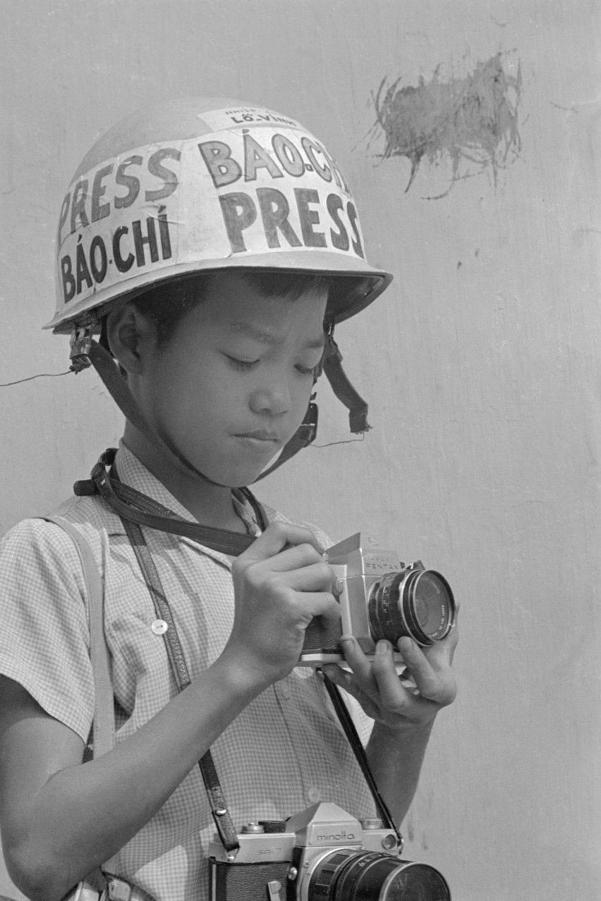 Imagen de jimmy con una cámara en sus manos y un casco que dice "prensa".