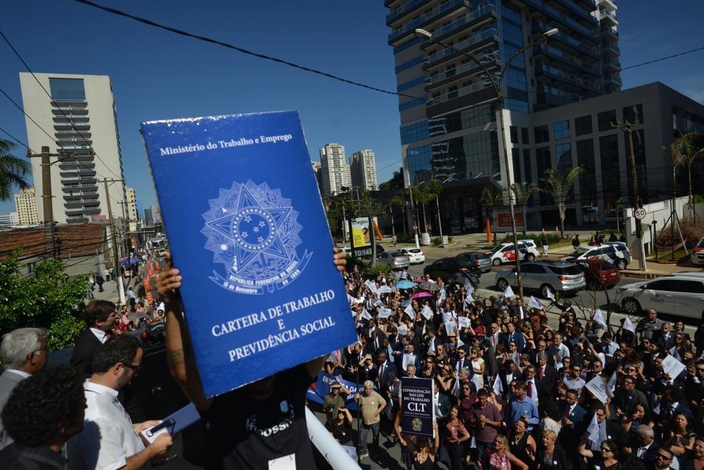 Manifestantes seguram uma carteira de trabalho gigante durante protesto em S&atilde;o Paulo