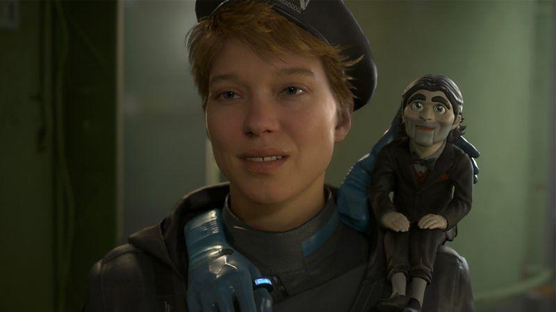 Cena de 'Death Stranding 2' com uma mulher e um boneco de ventr&iacute;loquo no ombro