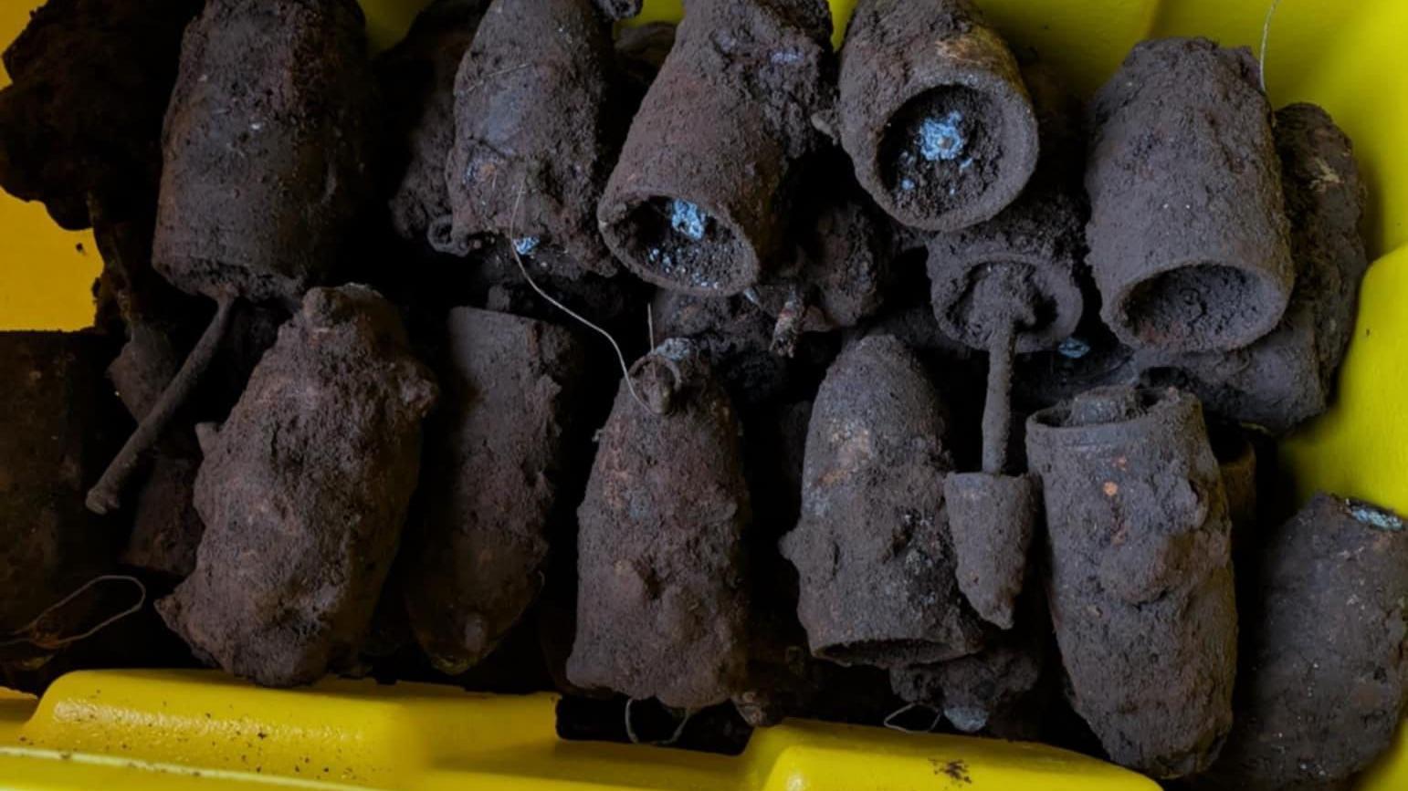 Uma caixa amarela com cerca de 20 bombas da Segunda Guerra Mundial cobertas de lama, mas com uma carga ainda visível na maioria delas