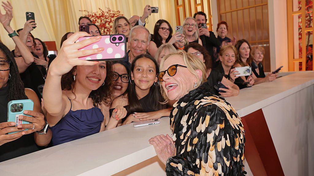 Žena sa naočarima za sunce se slika sa desetinama ljudi 