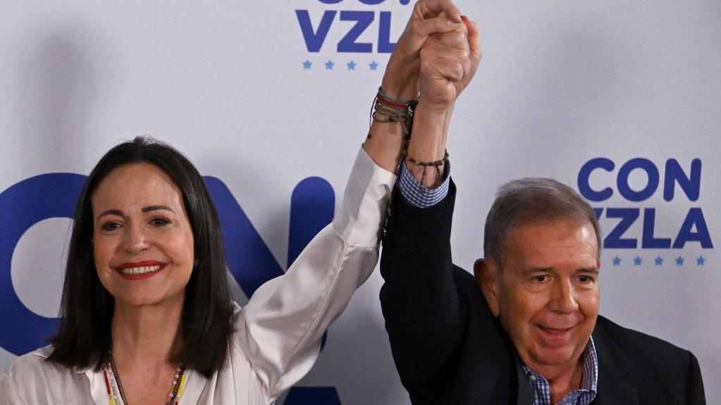 La líder opositora venezolana, María Corina Machado, saluda con la mano al candidato presidencial opositor, Edmundo González Urrutia, en Caracas el 29 de julio de 2024, un día después de las elecciones presidenciales venezolanas.