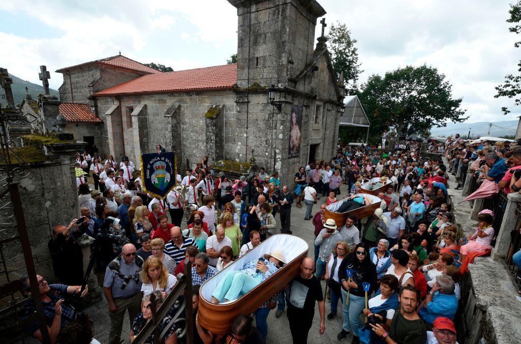 Personas llevan a hombros ataúdes abiertos frente a la ilglesia de San José de Ribarteme.