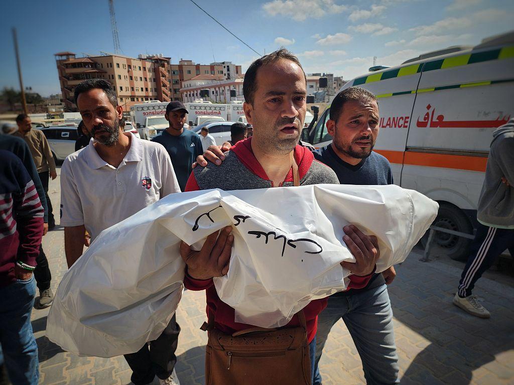 فلسطيني يحمل جثة طفل قُتل نتيجة الهجمات الإسرائيلية على خان يونس