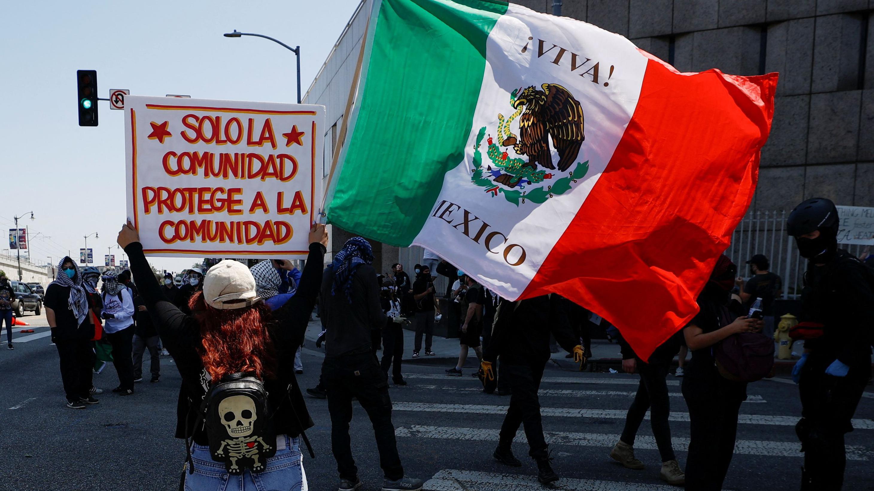 Una manifestante sostiene una bandera mexicana y un cartel que dice 'solo la comunidad protege a la comunidad', durante una protesta contra las redadas federales de inmigración, tras el despliegue de miembros de la Guardia Nacional de California fuera del edificio federal Edward R. Roybal por el presidente de EE. UU. Donald Trump en respuesta a las protestas, en Los Ángeles, California, EE. UU., 8 de junio de 2025. REUTERS/Mike Blake