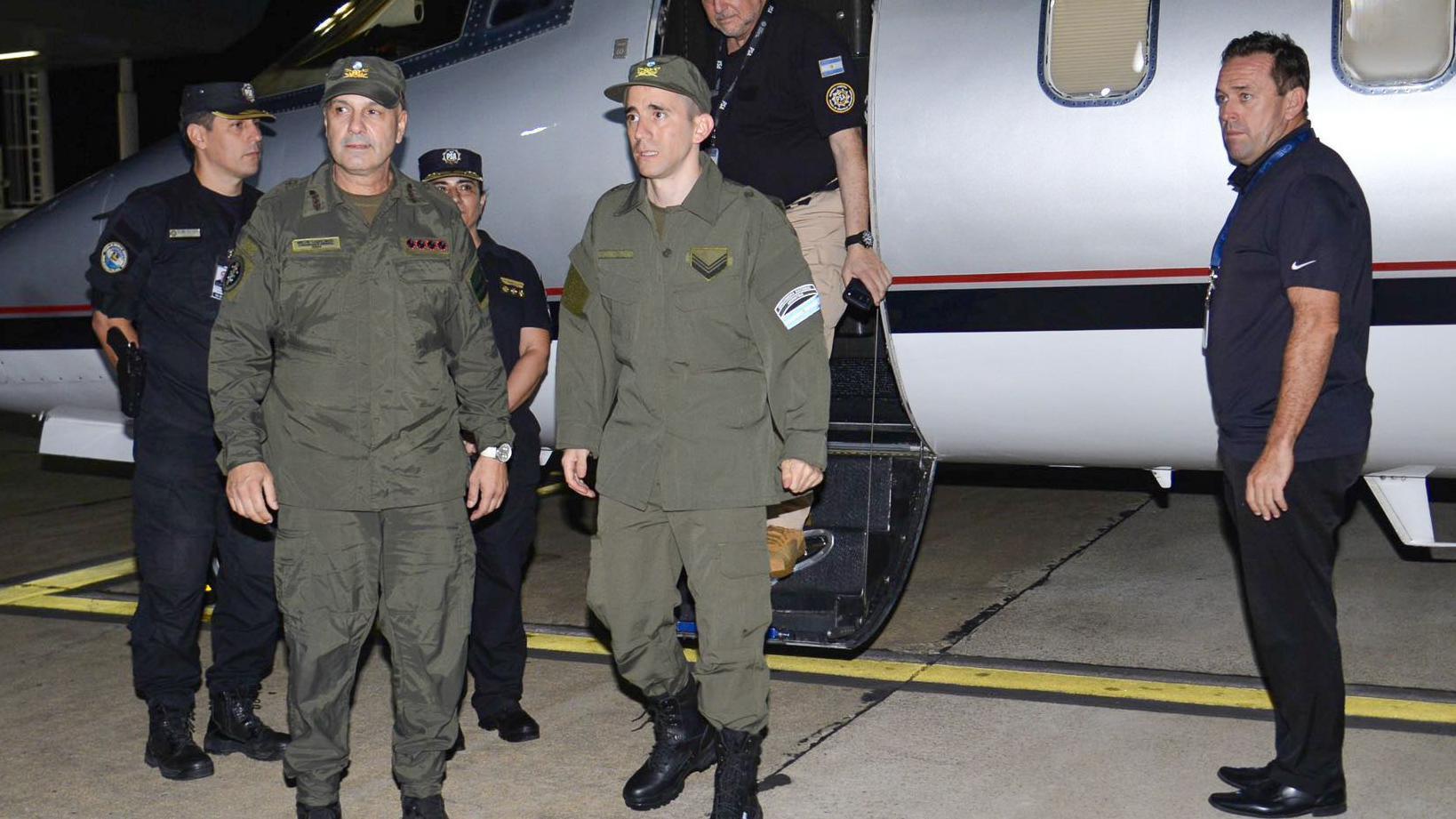 Nahuel Gallo (centro), vestido con su uniforme color verde militar, bajando del avión privado. A su lado ahy 