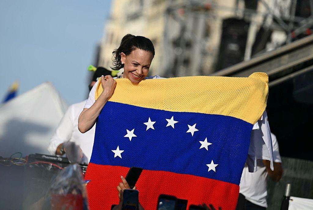 La líder opositora venezolana María Corina Machado sostiene una bandera de Venezuela mientras sus partidarios se reúnen en la Puerta del Sol de Madrid el 18 de abril de 2026.