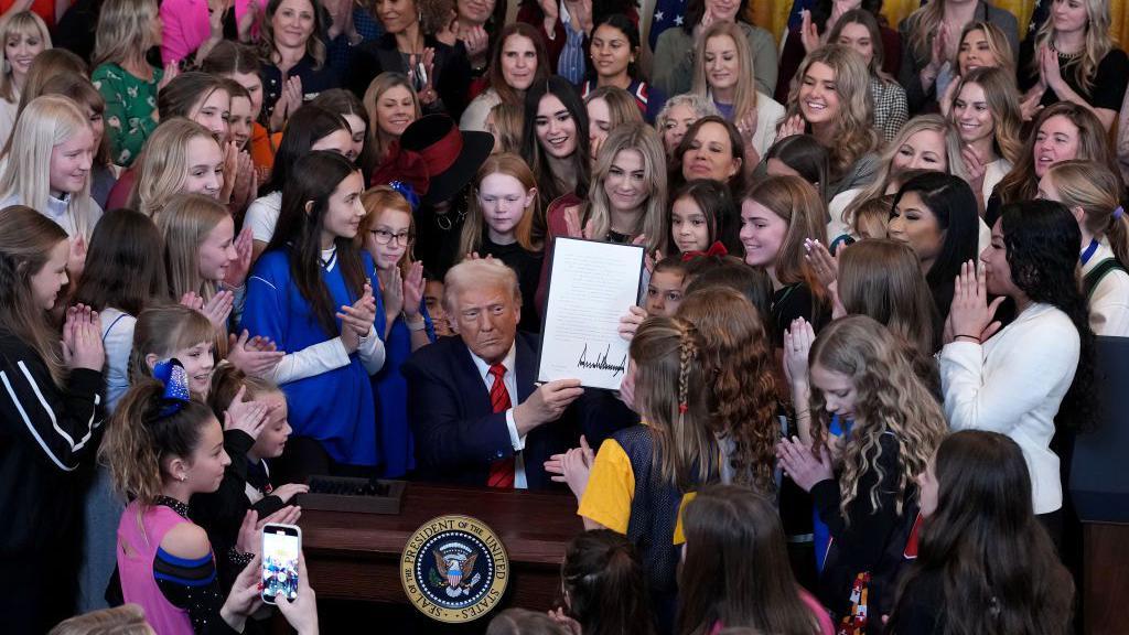 El presidente de EE.UU., Donald Trump, acompañado de atletas mujeres, muestra la orden ejecutiva recién firmada y titulada "No hombres en los deportes de mujeres" en el Salón Este de la Casa Blanca el 5 de febrero de 2025 en Washington, DC. Foto de Andrew Harnik/Getty Images