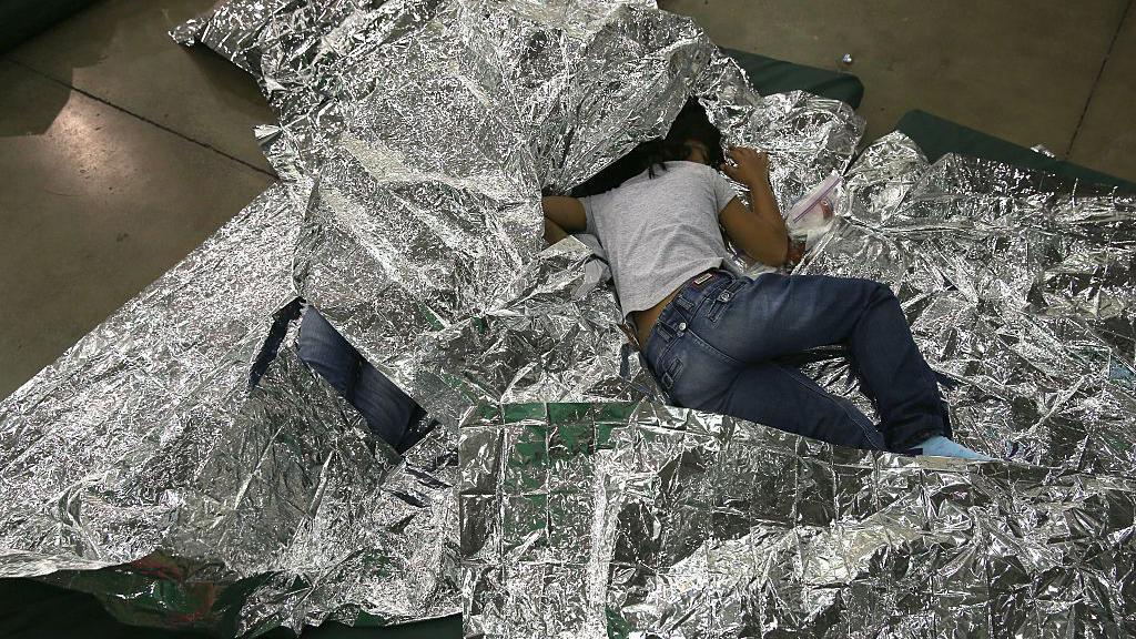 Una niña centroamericana duerme en el suelo, sobre una manta térmica plateada, en un centro de detención de la Patrulla Fronteriza de Estados Unidos en McAllen, Texas, el 8 de septiembre de 2014. (Foto: John Moore/Getty Images)