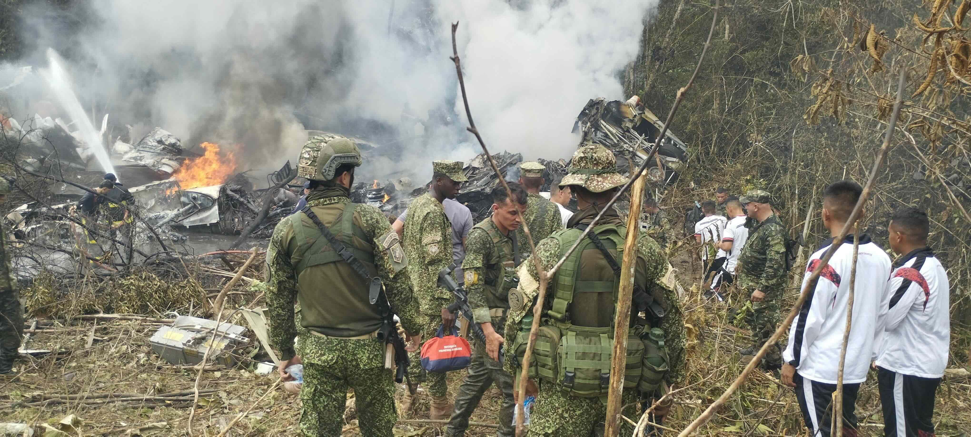 Varios soldados están parados alrededor del sitio del accidente del avión Hércules de la Fuerza Aérea Colombiana (FAC)