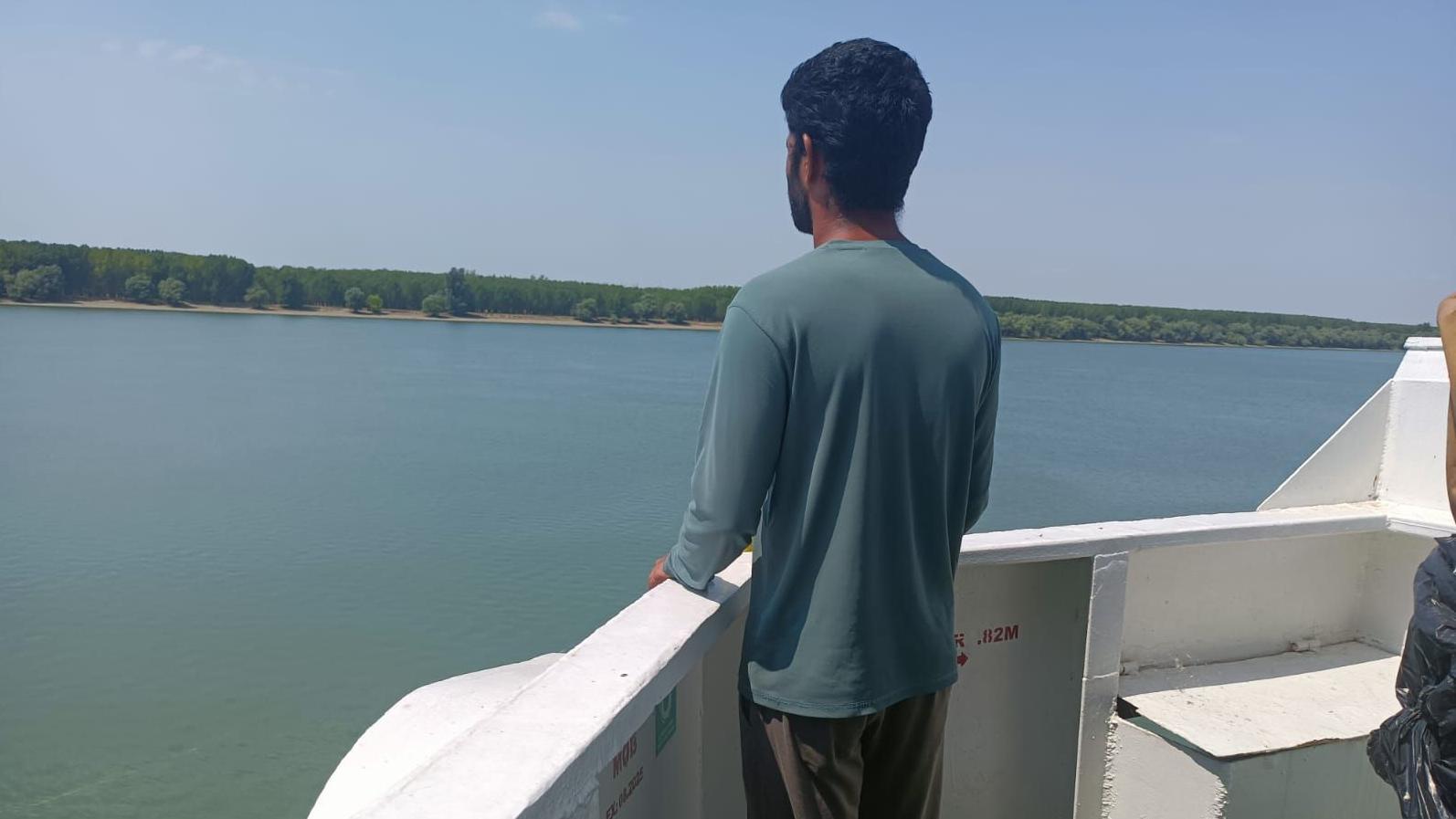 Un tripulante del carguero Anka, abandonado en un puerto ucraniano en un río que divide Ucrania y Rumanía, con camisa azul, observa la extensión del río desde la proa del buque.