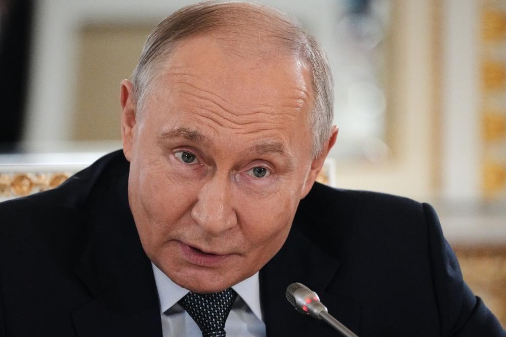 Putin, vestido com um terno escuro, camisa clara e gravata de bolinhas, fala ao microfone, em uma coletiva de imprensa