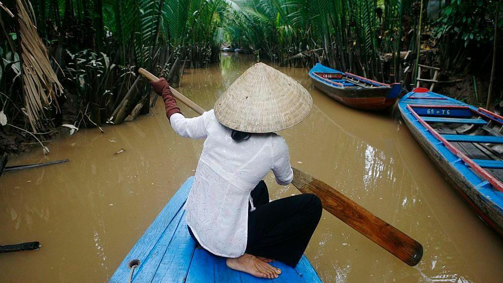 Una mujer vietnamita navega en su bote por un pequeño afluente del río Tien en My Tho.