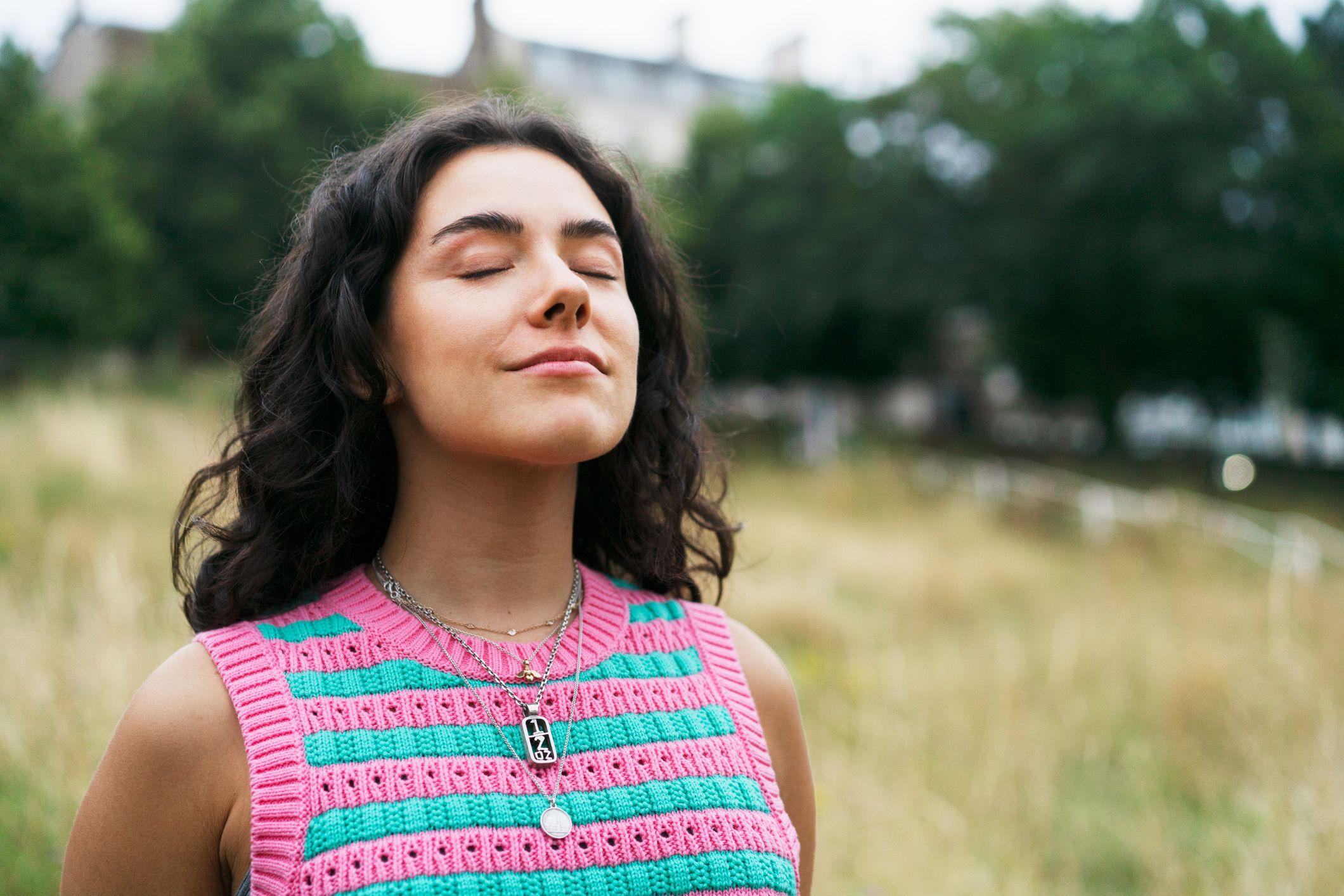 Una mujer con un jersey rayado y sus ojos cerrados parece estar en completa paz. 