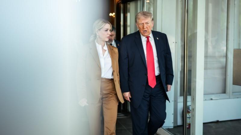 Trump e Bondi caminhando lado a lado na Suprema Corte dos EUA em 1&ordm; de abril de 2026. Ela veste terno feminino bege e camisa branca e ele usa um terno azul marinho com gravata vermelha e camisa branca