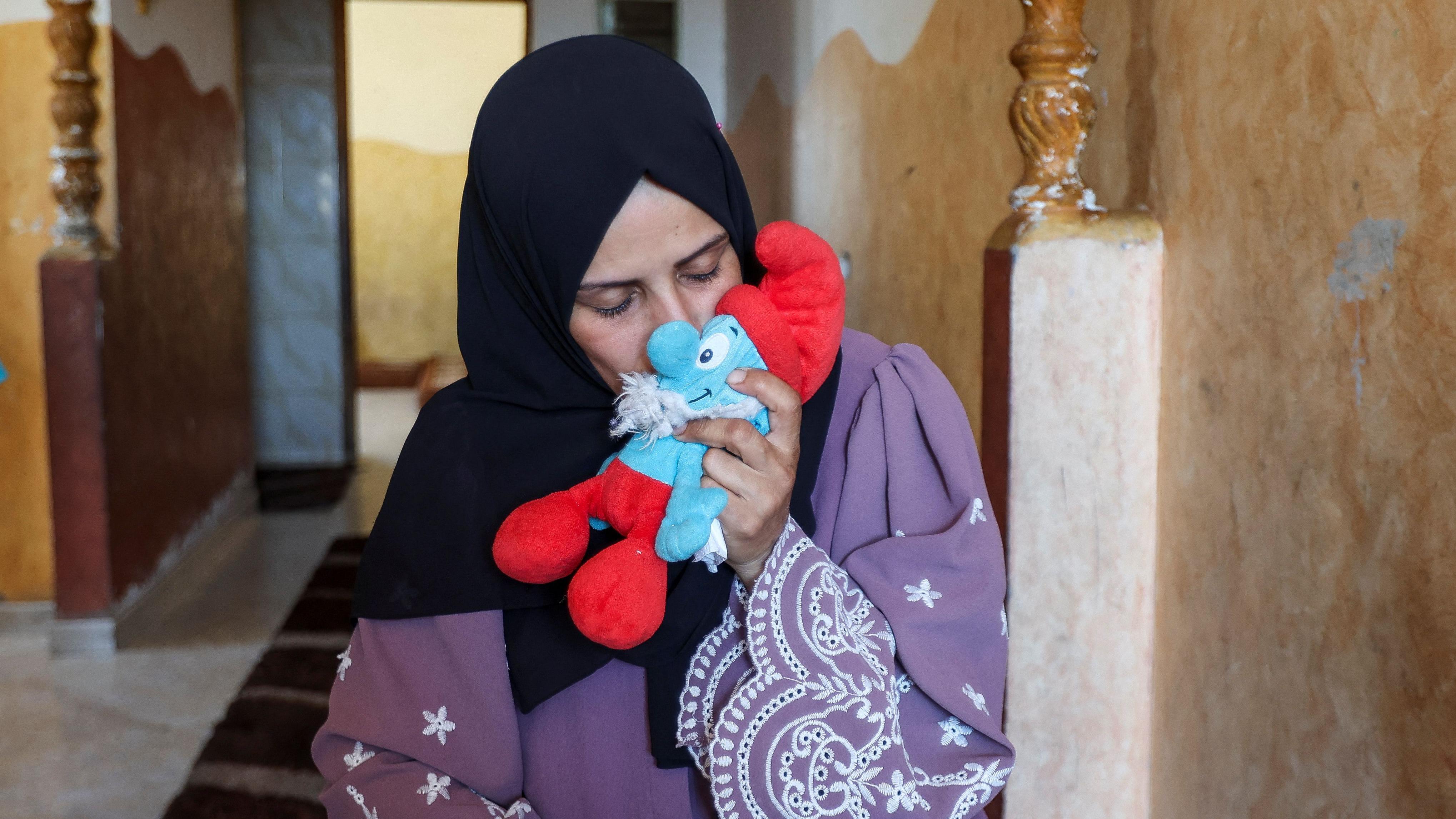 سيدة فلسطينية تحمل دمية لأحد أطفالها الذي قُتلوا في قصف إسرائيلي 