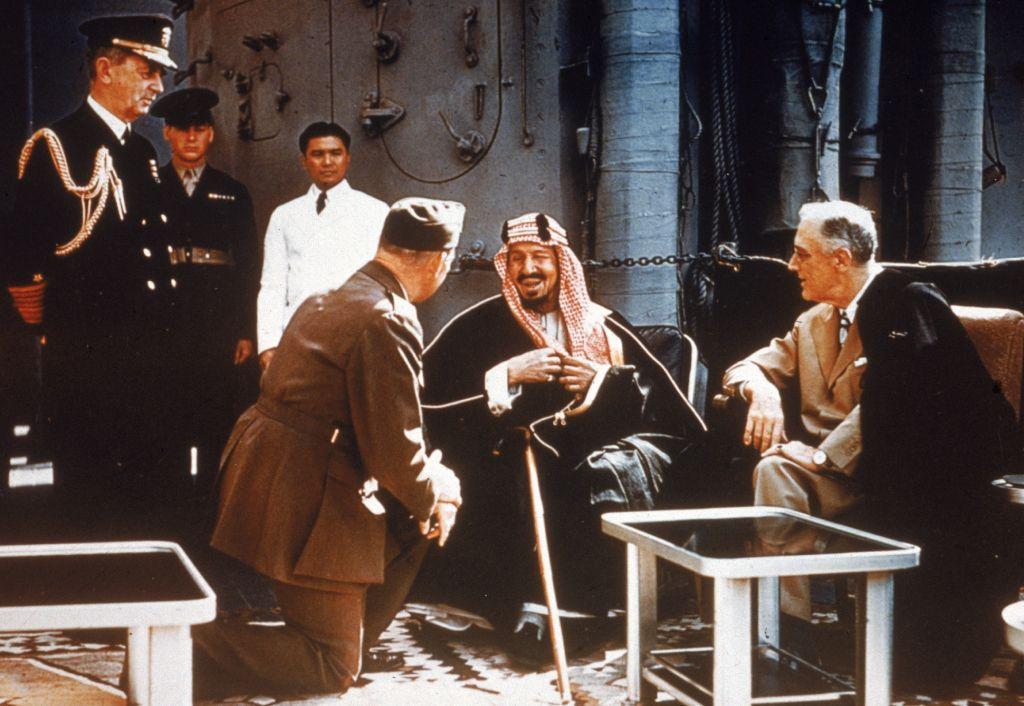El presidente estadounidense Franklin Delano Roosevelt reunido con el rey Ibn Saud de Arabia Saudita, el jefe de Estado Mayor William D. Leahy (de rodillas) y el coronel William A. Eddy, a bordo del USS Quincy en el Canal de Suez, Egipto, el 14 de febrero de 1945. 