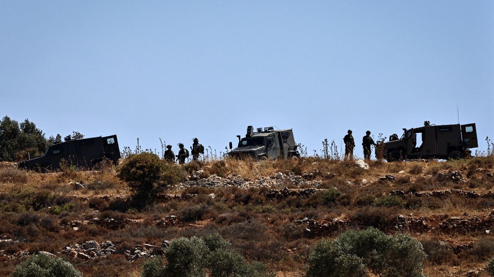 جنود من الجيش الإسرائيلي يتخذون موقعاً على تلة قرب قرية سنجل، في الضفة الغربية المحتلة، في 18 يوليو/تموز 2025، بعد مقتل فلسطينيين يحملان الجنسية المزدوجة في اشتباكات مع مستوطنين إسرائيليين. 