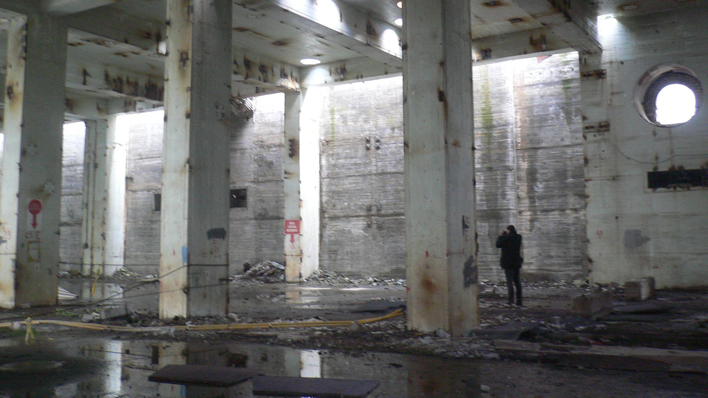 Pessoa tirando fotografias em um edifício vazio de altas colunas na central nuclear de Lemóniz, na Espanha