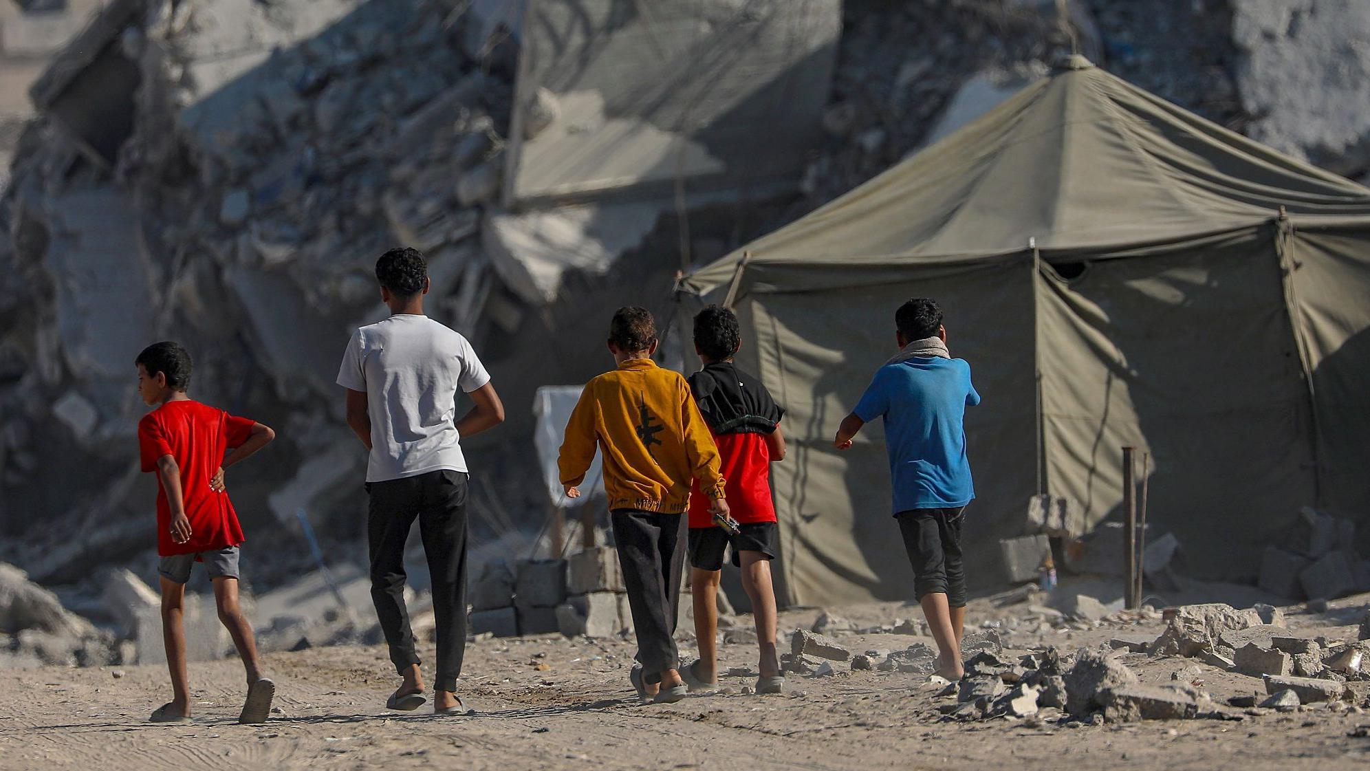 Dečaci šetaju razrušenim ulicama Gaze, okrenuti su leđima ka kameri