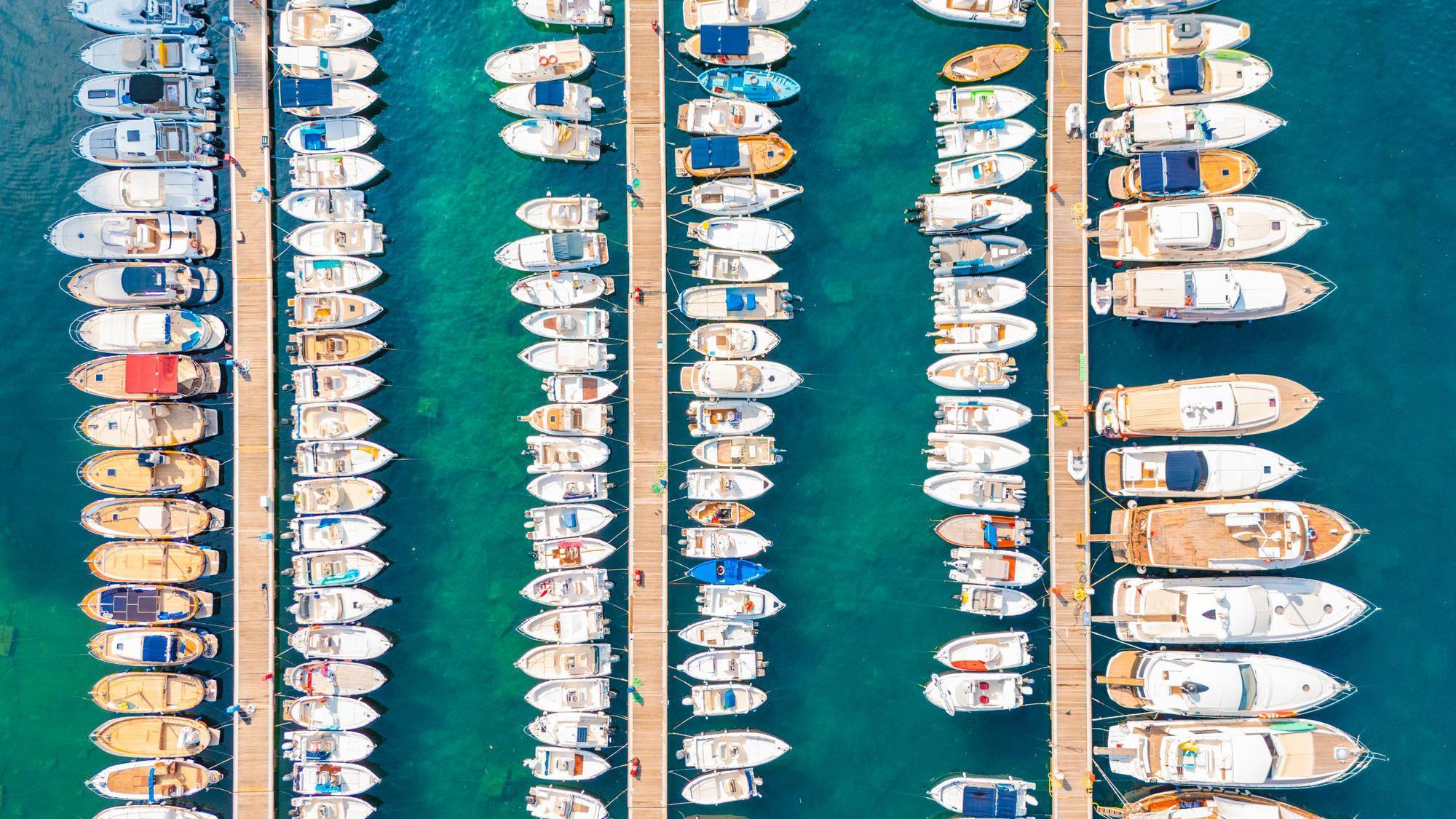 從空中俯瞰，擁擠的遊艇碼頭，碧綠的海水中停泊著一排排遊艇。