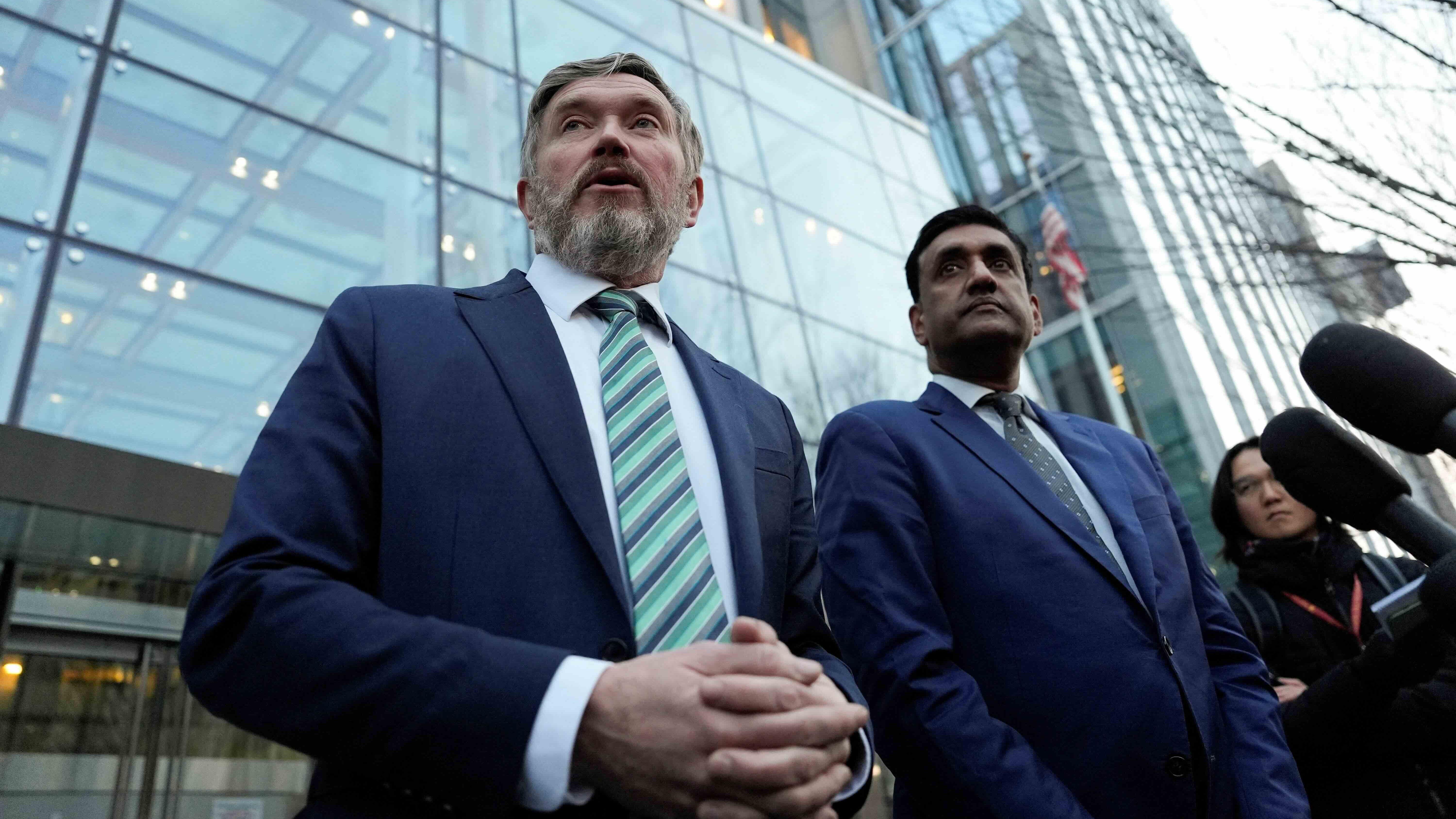 Ro Khanna y Thomas Massieestán frente a un edificio de vidrio mientras varios micrófonos apuntan hacia ellos.