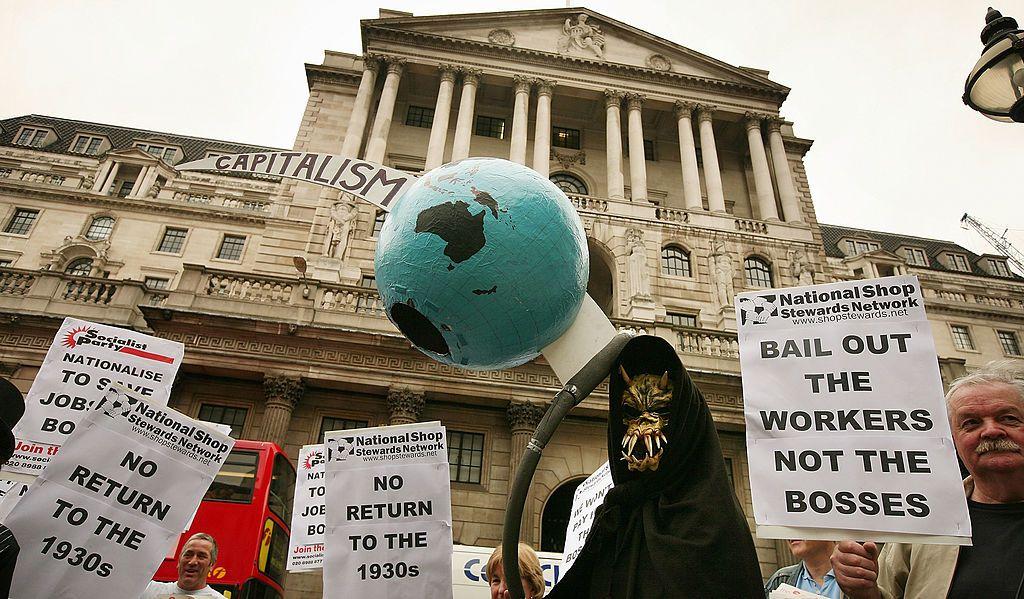 Uma figura da Morte segura um globo terrestre atravessado por uma foice em frente ao Banco da Inglaterra durante um protesto em 13 de outubro de 2008 em Londres