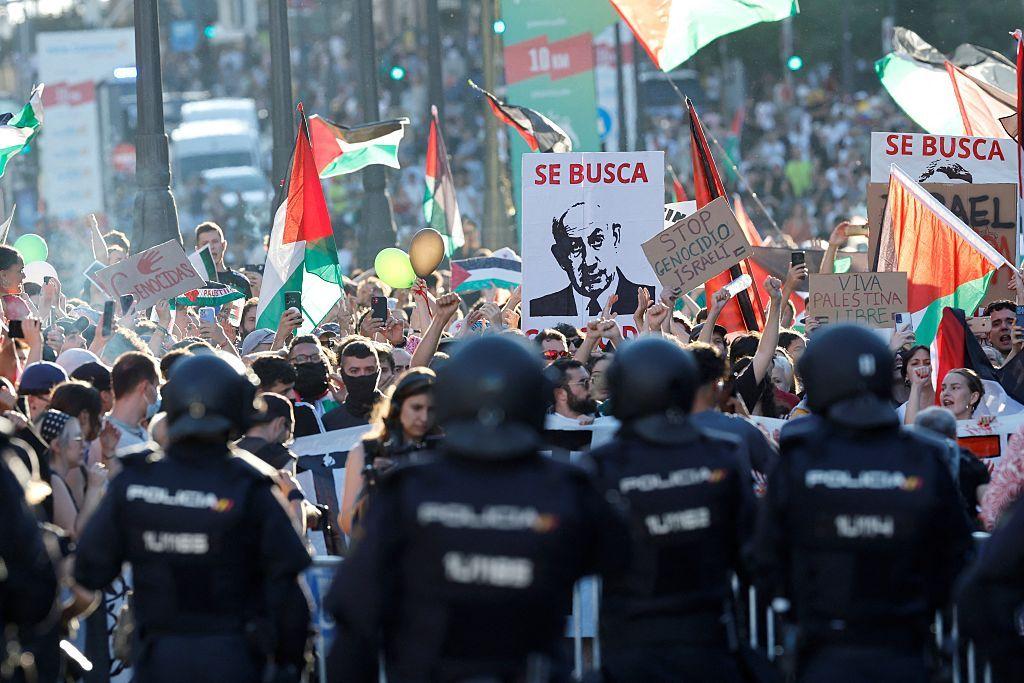 Manifestantes propalestinos con banderas y en primer plano un grupo de policías.