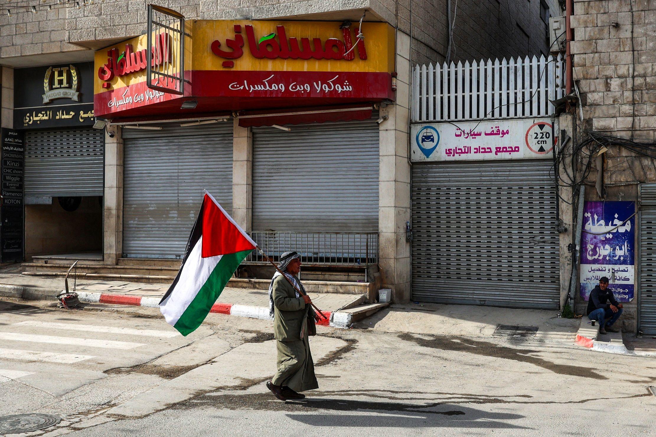الفلسطينيون، بثلاثة مناصب رئاسية، وحكومة، وبلا دولة 7 رجل يحمل العلم الفلسطيني في مدينة جنين في الضفة الغربية المحتلة في 10 ديسمبر/كانون الأول 2024
